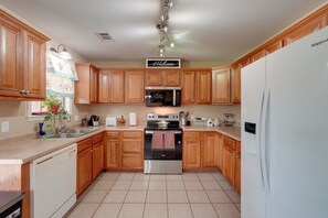Una cocina con armarios de madera, horno de acero inoxidable, microondas y refrigerador blanco.