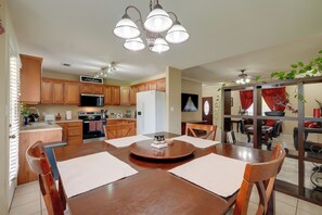 Una cocina con armarios de madera, microondas y un comedor con mesa y sillas de madera.