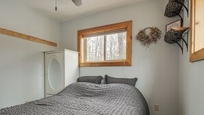 Ein Schlafzimmer mit Bett, Fenster, Kleiderhaken und Kleiderschrank.