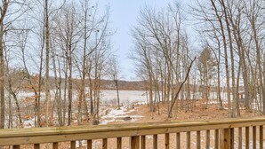Une terrasse en bois offrant une vue sur une zone boisée et un plan d’eau.