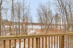 A wooden deck with a view of a forested area and a body of water.