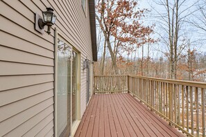 A wooden deck with a glass door and a lantern on the house's exterior wall.