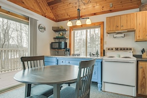 A kitchen with wooden cabinets, a white stove, a round table, and chairs.