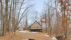 Une cabane dotée d’une terrasse, entourée d’arbres et surplombant un paysage enneigé.