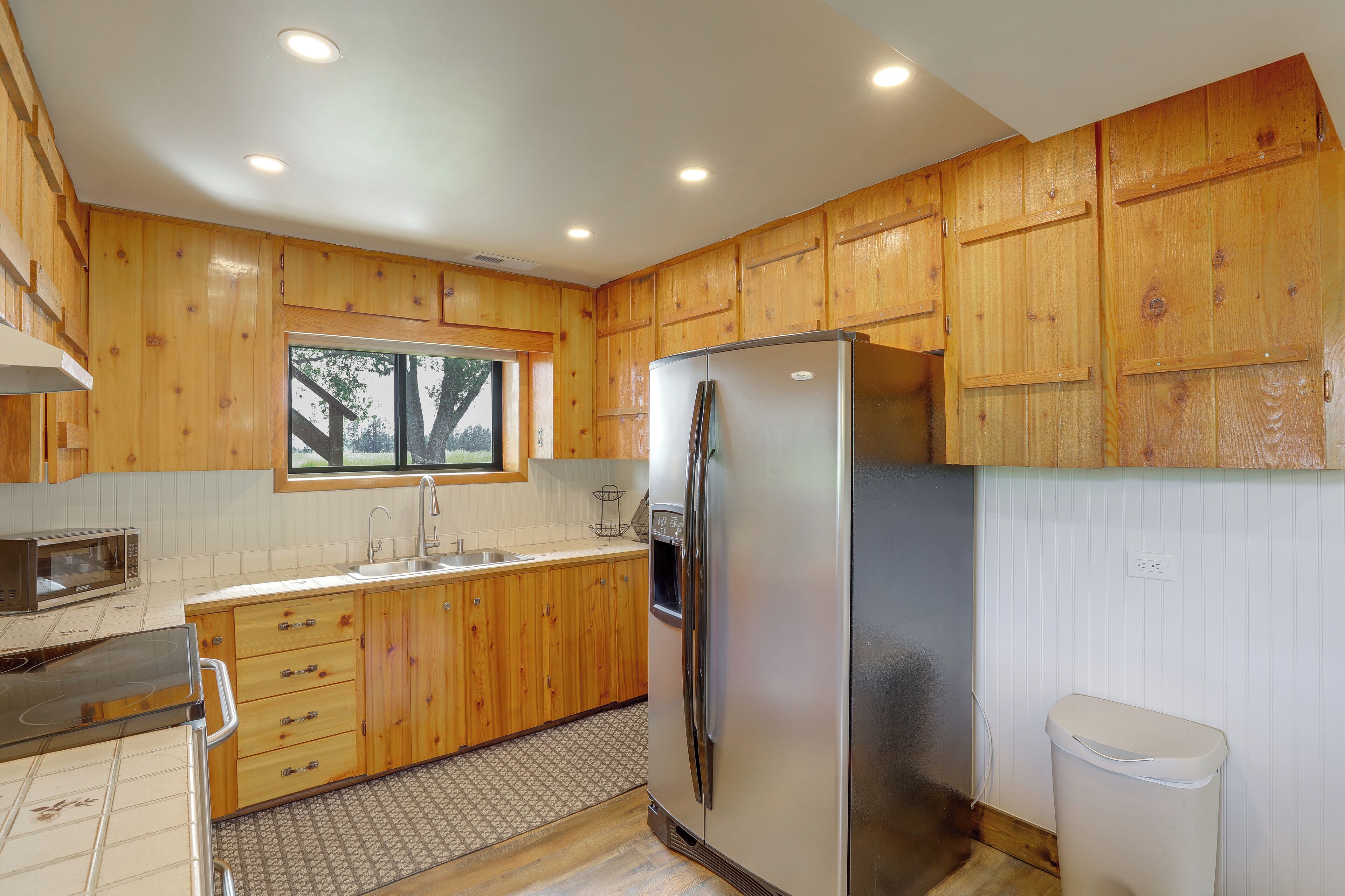 A kitchen with wooden cabinets, a stainless steel refrigerator, a microwave, and a sink.
