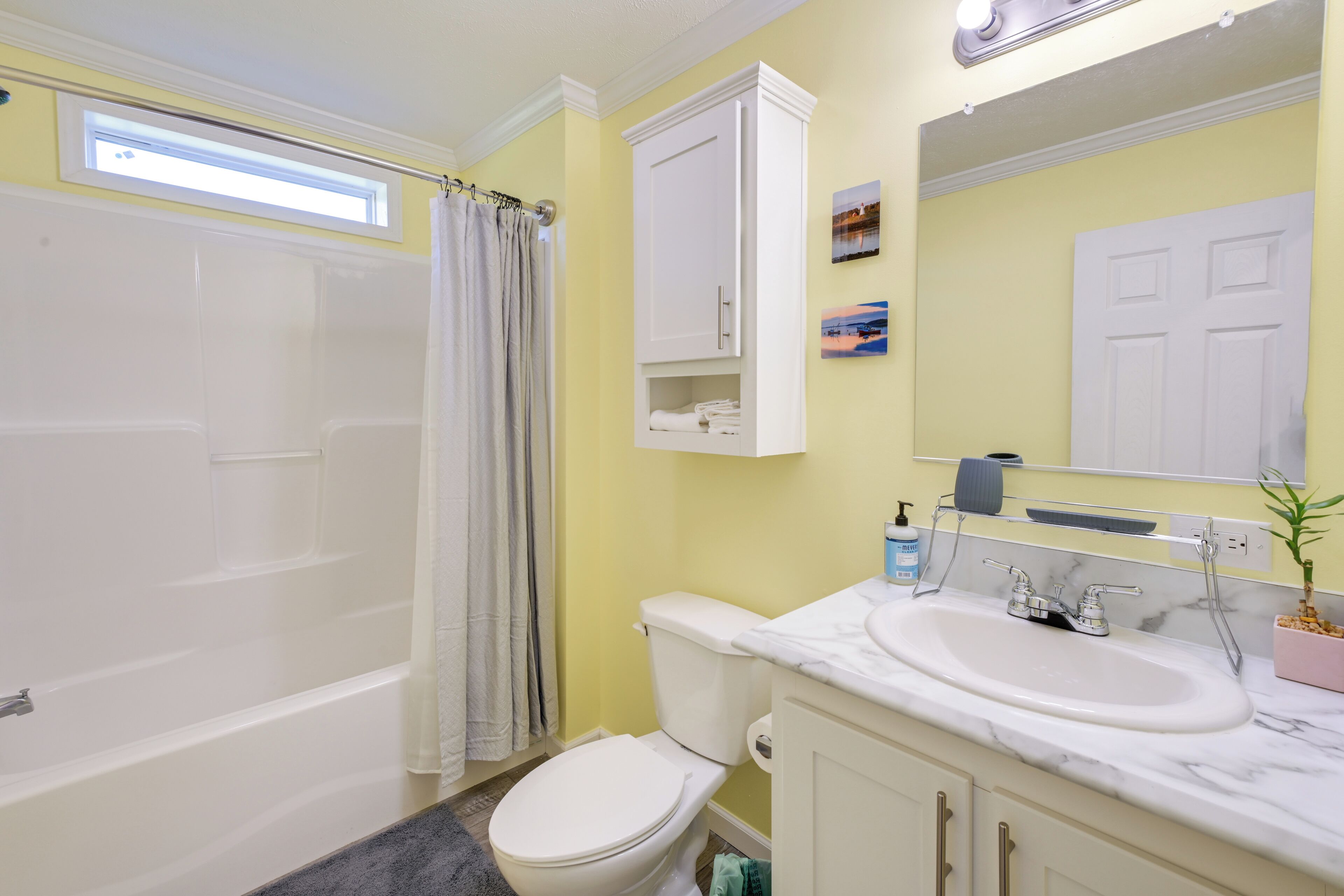 A bathroom with a bathtub, toilet, sink, and a window above the shower.