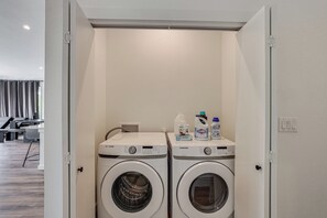 Ein Waschraum mit zwei Samsung Waschmaschinen, einem Wäscheständer und einer Waschmittelflasche.
