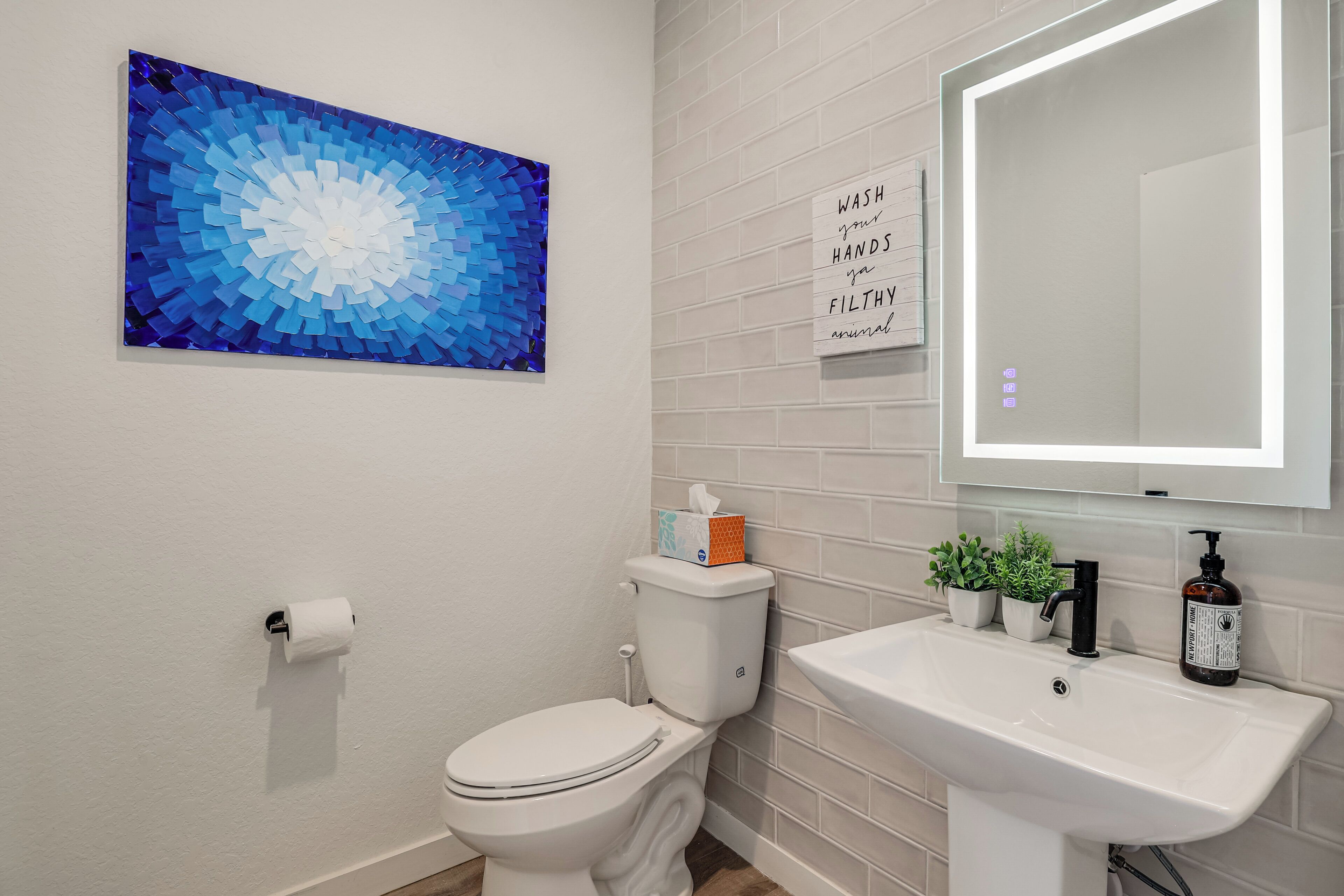 Et badeværelse med toilet, håndvask og et spejl på væggen.