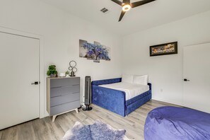 Ein Schlafzimmer mit Bett, Kommode, Deckenventilator, Kunstwerken und einem Schild an der Wand.