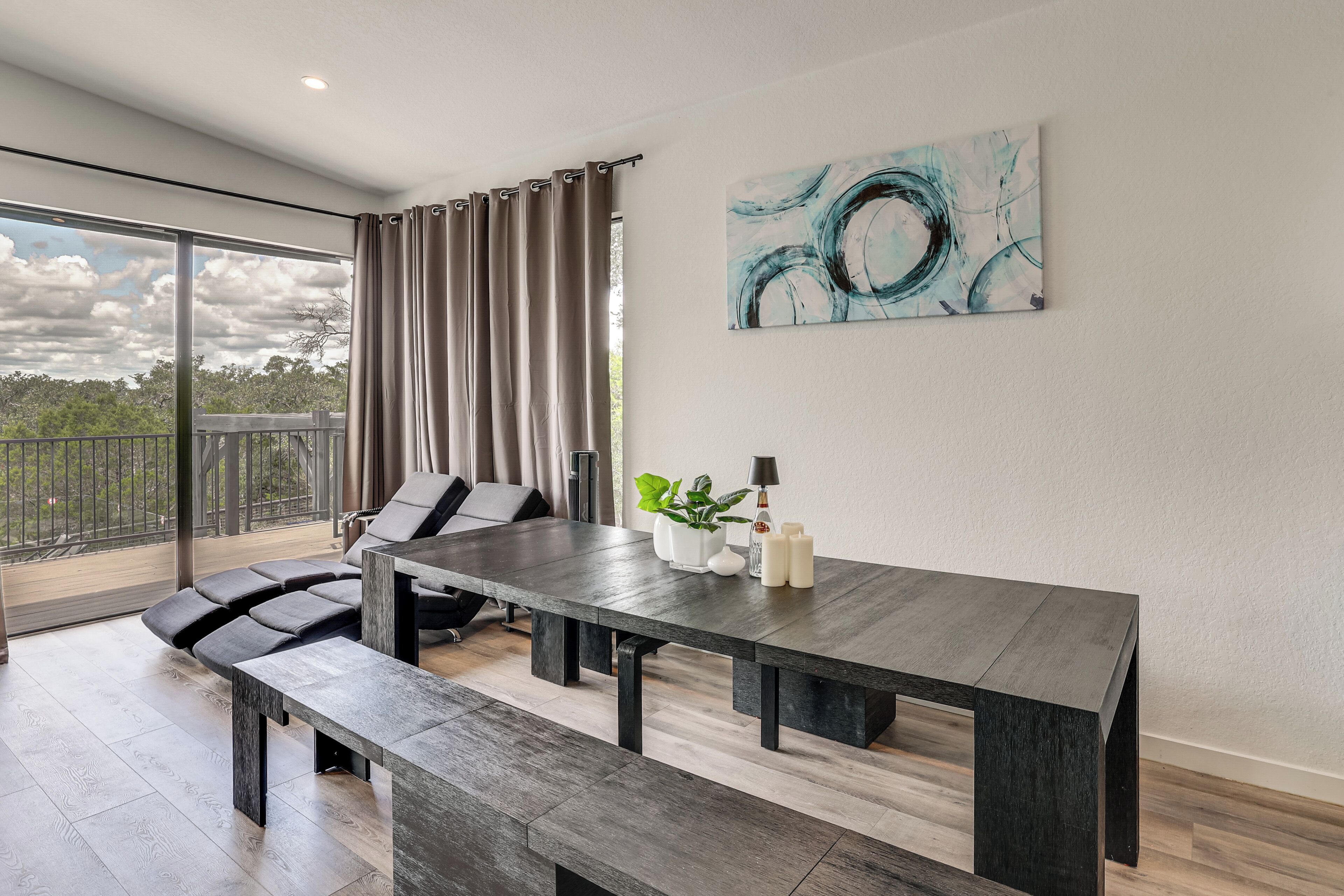 Un espace repas moderne avec une table en bois foncé, des bancs et une vue sur la verdure grâce à de grandes fenêtres.