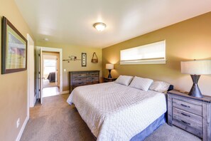 A bedroom with a bed, bedside tables, a lamp, a window, and a door leading to another room. - 4 Mi to Dtwn! Columbia Falls Home w/ Spacious Yard (Columbia Falls)