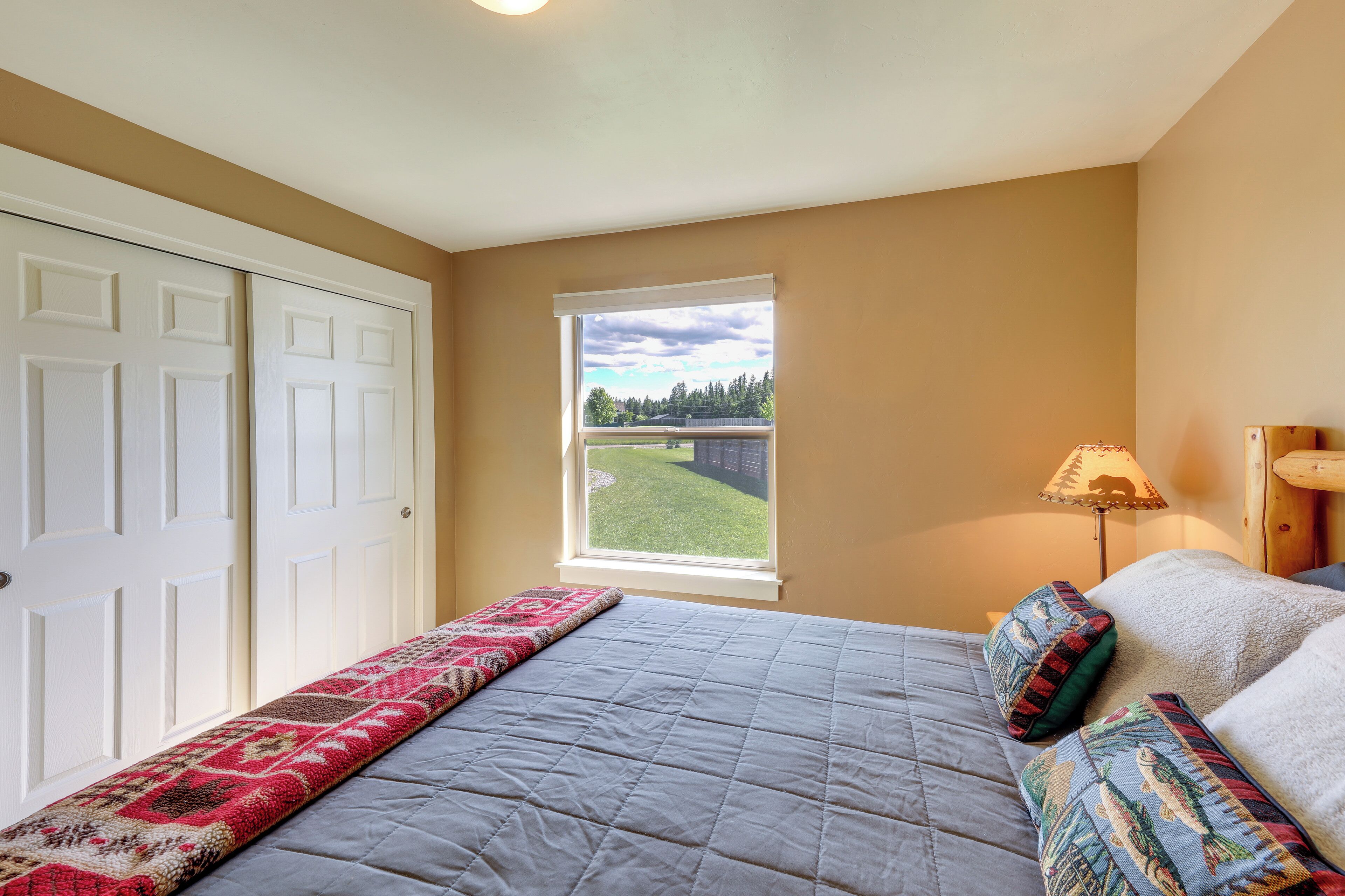 Un dormitorio con cama, ventana con vistas, puerta y lámpara.