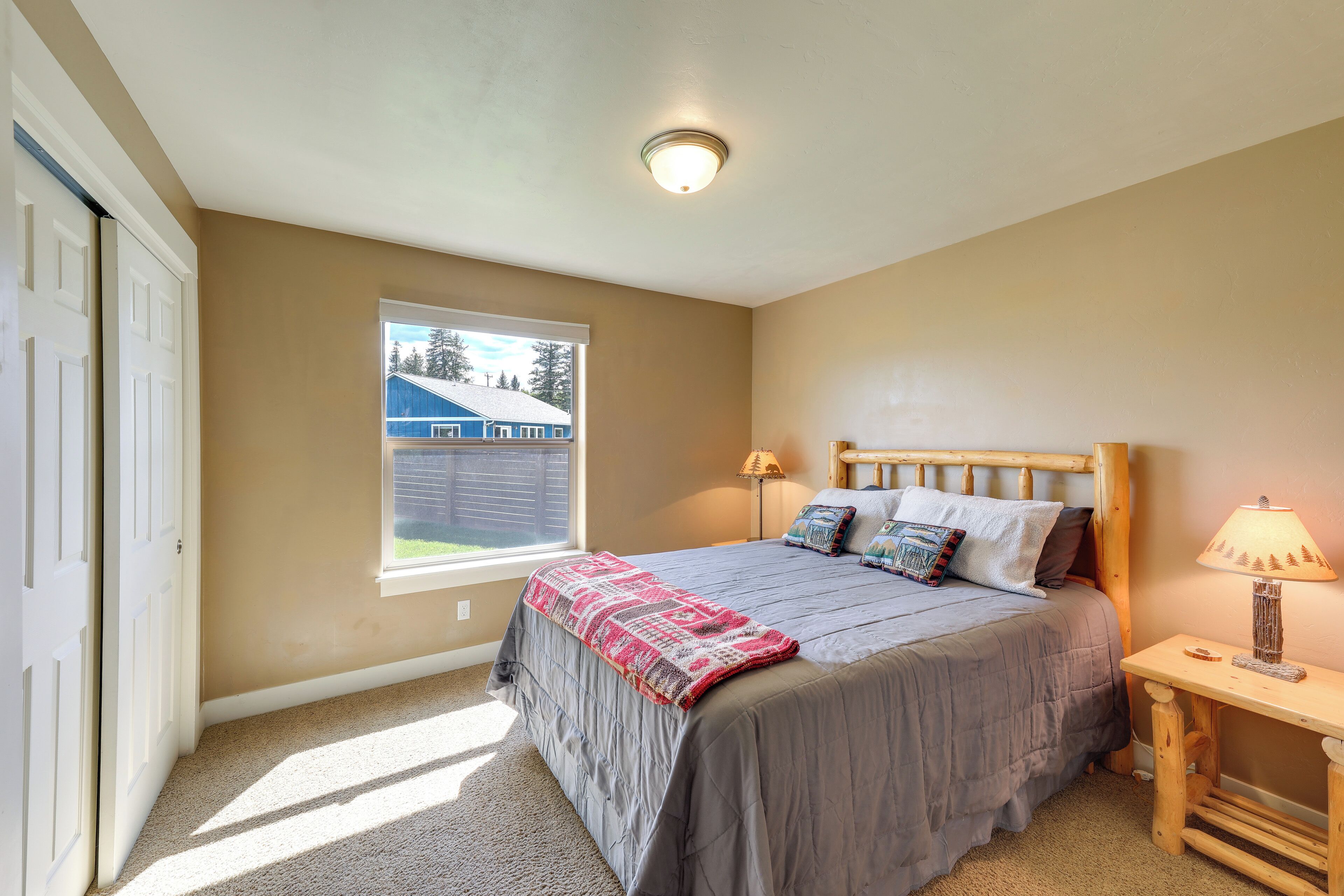 A bedroom with a bed, a window, a bedside table, and a lamp.