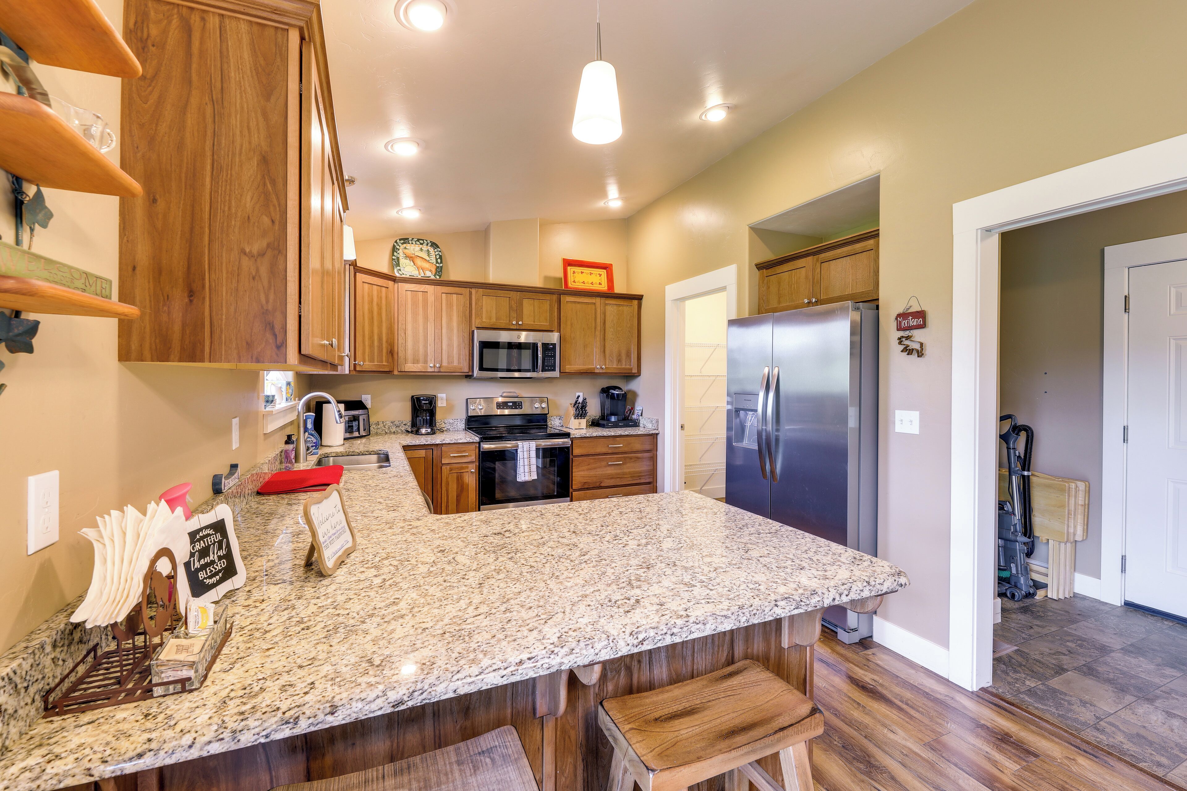 A kitchen with wooden cabinets, a granite countertop, a stainless steel refrigerator, and a microwave.