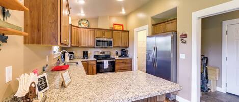 A kitchen with wooden cabinets, a granite countertop, a stainless steel refrigerator, and a microwave.