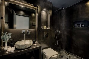 Une salle de bain moderne avec un grand miroir, un lavabo en marbre, une douche et une étagère contenant des articles de toilette.