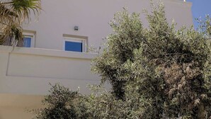 Ein Gebäude mit weißer Fassade, einem Fenster mit blauer Umrandung und einem Balkon mit Geländer.