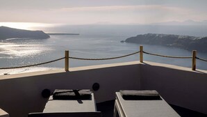 Ein Balkon mit Geländer aus Seil, zwei Liegestühlen und Blick auf ein Gewässer mit weiter Landschaft.
