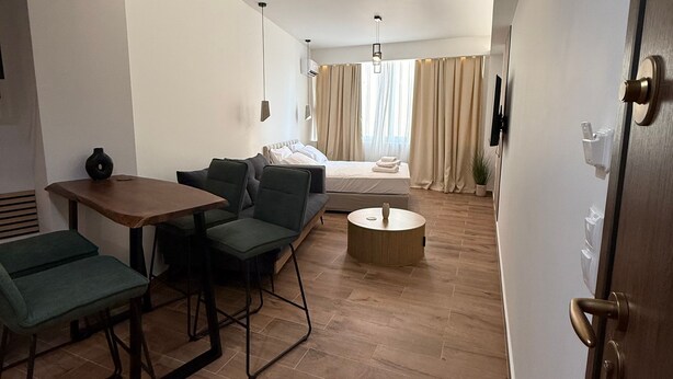 A modern living room with a sofa, a dining table, and a coffee table. - Athenian Stay 305 Apartment Monastiraki (Athens)