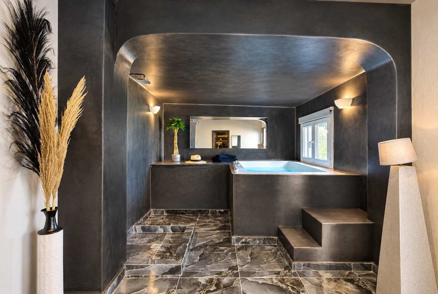 Een moderne badkamer met een marmeren vloer, een inbouwhaardbad en een grote spiegel.