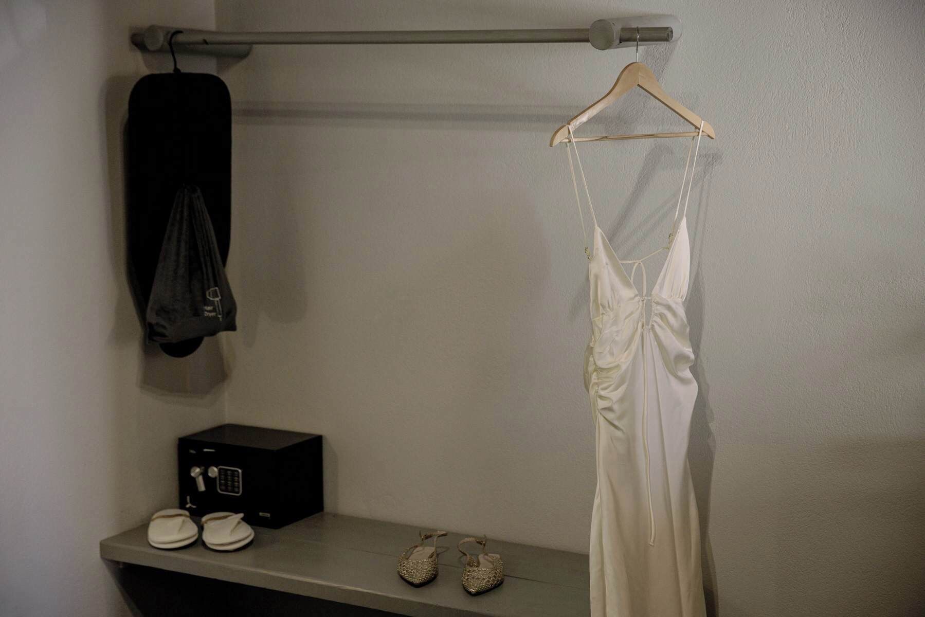 A room with a hanging garment rack, a small black box, and a pair of shoes on a shelf.
