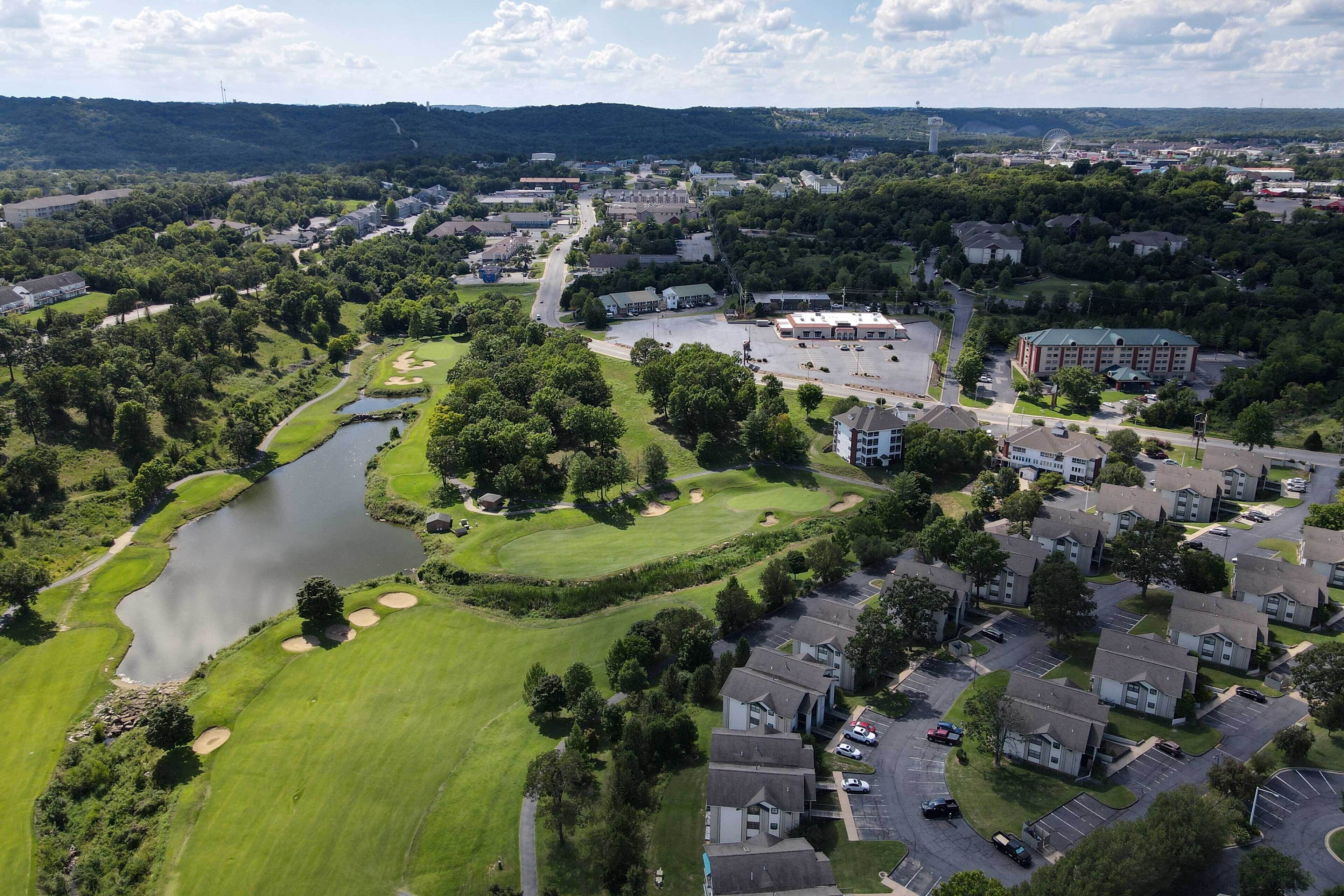 An aerial view of a residential area with a golf course, a body of water, and a parking lot.