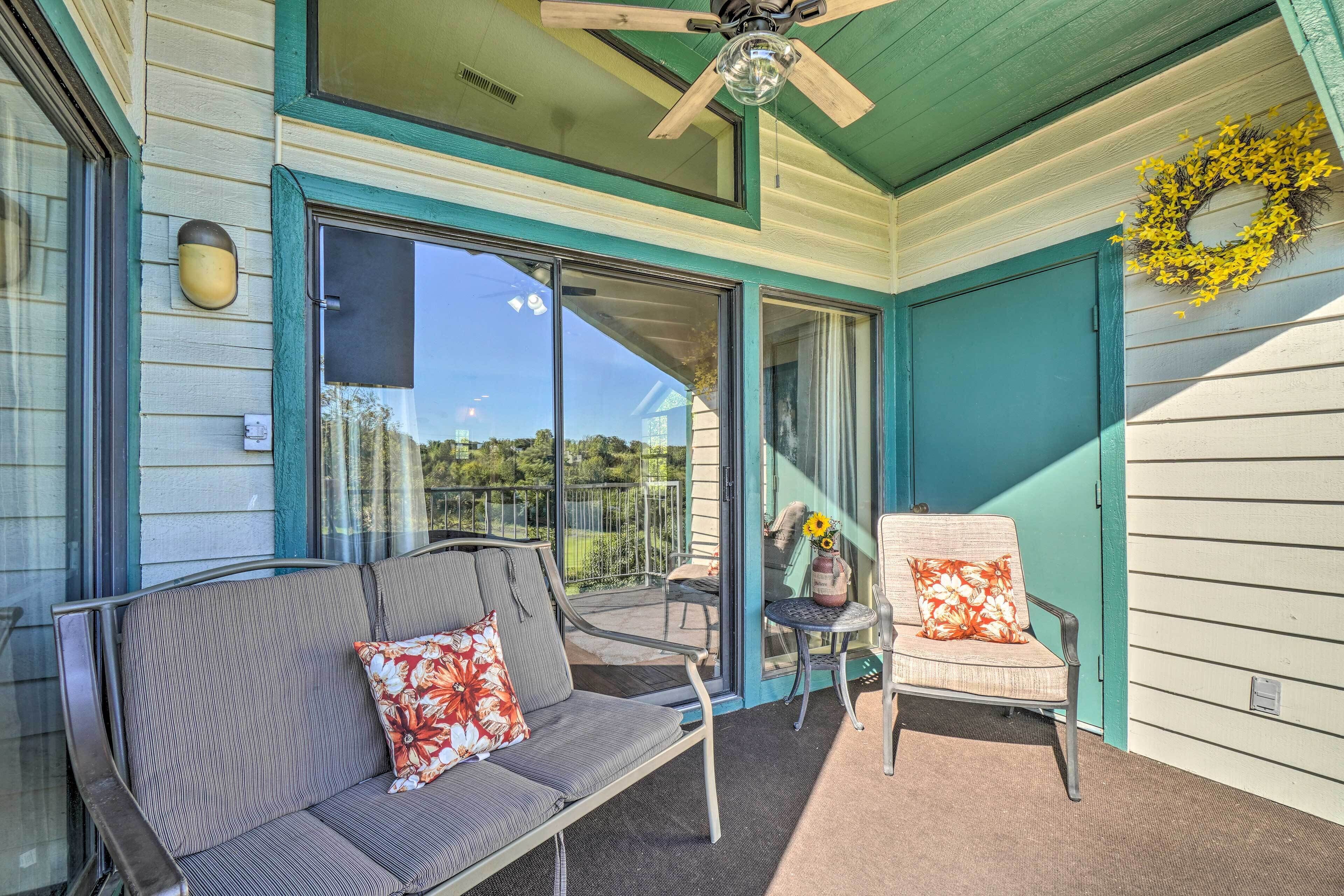 A covered porch with a bench and a chair, a ceiling fan, and a wreath on the wall.