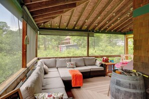 Un espace extérieur abrité, doté d’un plafond en bois, d’un canapé confortable, d’une table en bois et d’un tonneau.