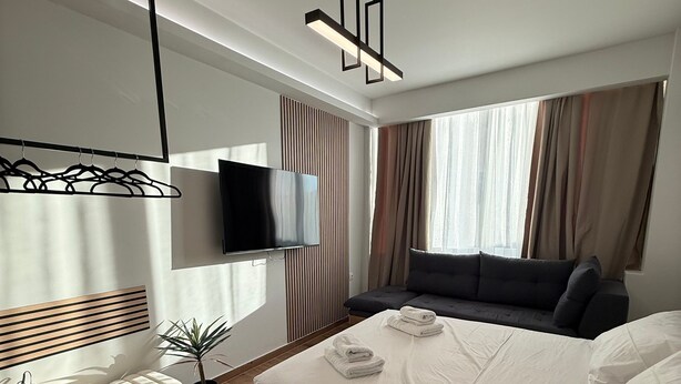 A modern hotel room with a bed, a TV, a bench, and a plant. - Athenian Stay 304 Monastiraki (Athens)