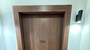 A wooden door with the number 304, a doormat with 'WELCOME', and a wall-mounted light fixture. - Athenian Stay 304 Monastiraki (Athens)