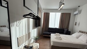 A modern hotel room with a large bed, a sofa, a TV, and a mirror. - Athenian Stay 304 Monastiraki (Athens)