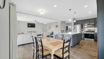 A modern kitchen with dark cabinets, a central island, and a dining area with a wooden table and chairs.