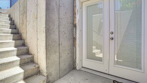Una escalera de hormigón que conduce a una puerta con un panel de vidrio.
