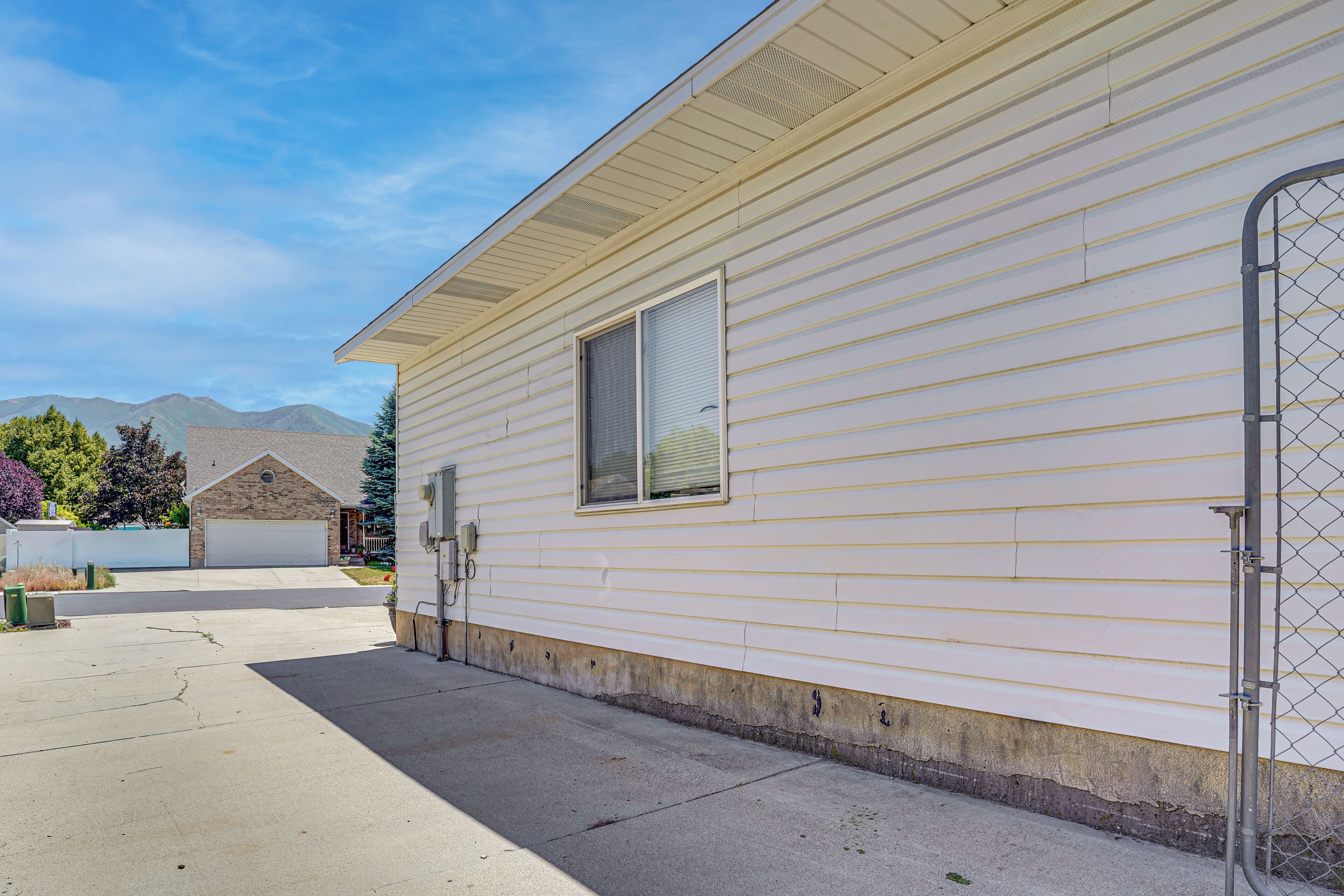 A single-story mobile home with a garage, a window, and a chain-link fence.