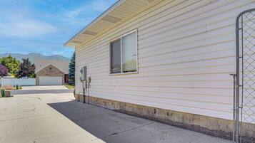 A single-story mobile home with a garage, a window, and a chain-link fence.