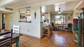A spacious kitchen with a dining area, featuring a stone-tiled floor, wooden chairs, and a rustic aesthetic. - Dual Tucson Rentals: Pool, Views & Space for All! (Tucson)