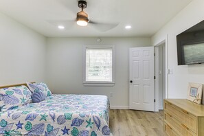 A bedroom with a bed, a window, a door, and a dresser.