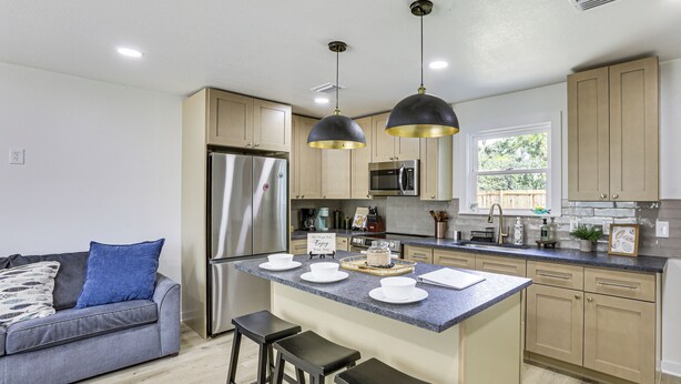 Una cocina moderna con una isla central, electrodomésticos de acero inoxidable e iluminación colgante.
