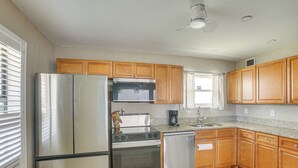Una cocina con gabinetes de madera, electrodomésticos de acero inoxidable y piso de baldosas.