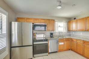 A kitchen with wooden cabinets, stainless steel appliances, and a tiled floor. - 4 Mi to Beach Park! Canal-front Port Charlotte Gem (Port Charlotte)
