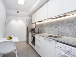 A modern kitchen with white cabinets, a granite countertop, a built-in microwave, a stainless steel sink, and a dishwasher. - CHL Apartamento Confort Güímar, Tenerife (Güimar)