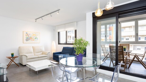 A modern living room with a glass dining table, clear chairs, a sofa, a coffee table, and a potted plant. - CHL Apartamento Confort Güímar, Tenerife (Güimar)