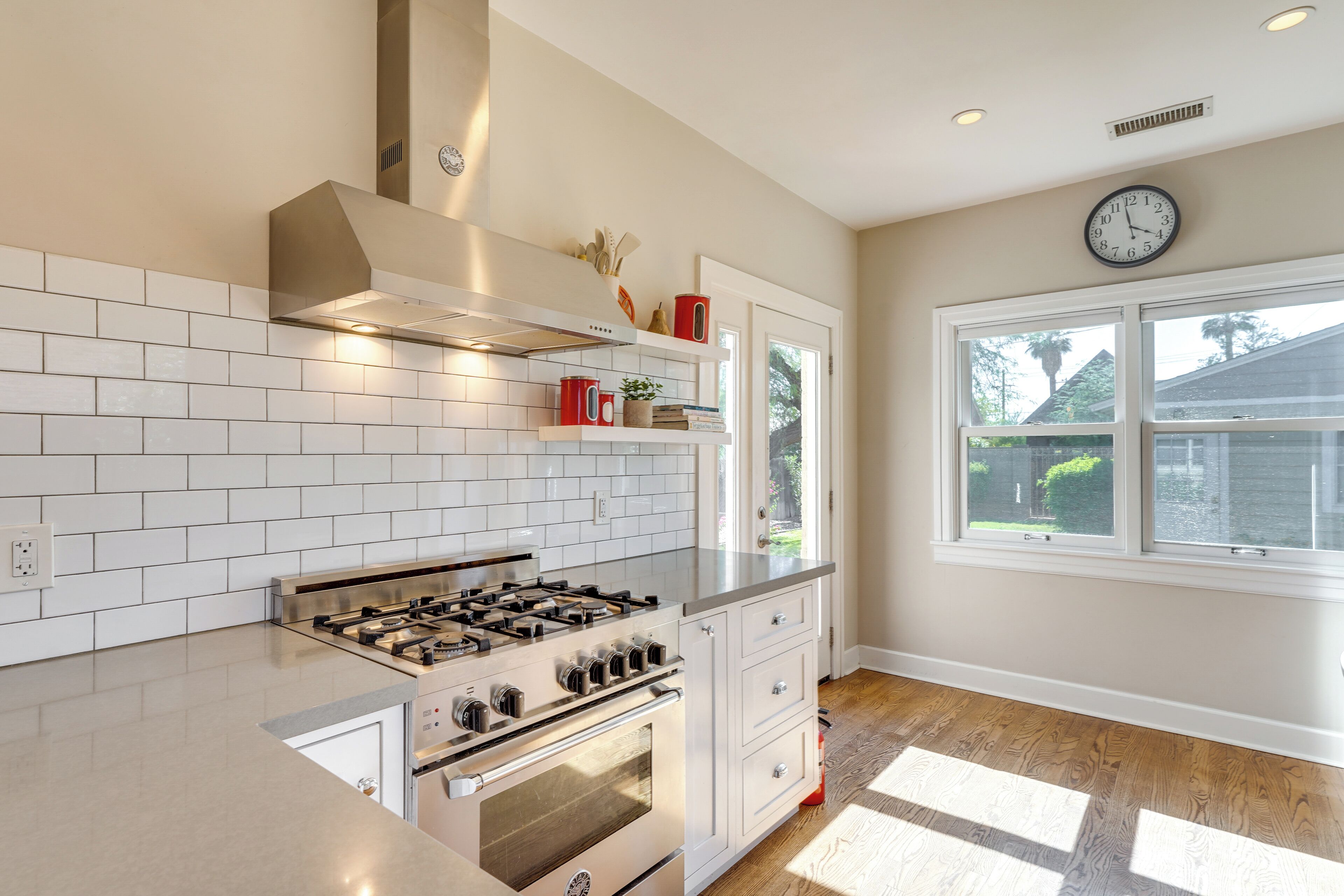 A modern kitchen with white cabinetry, a stainless steel range, and a window with a view of the outdoors.