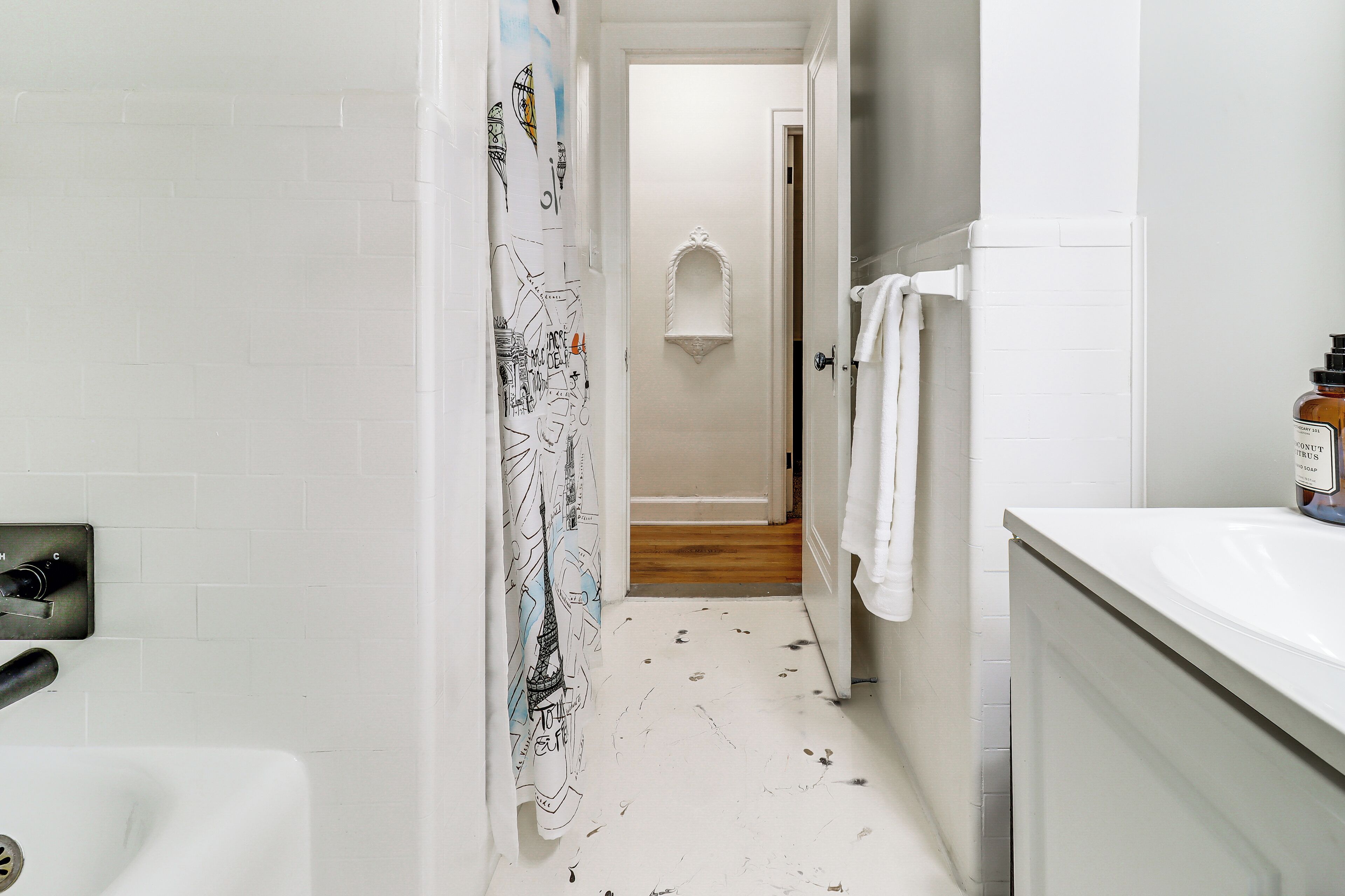 Un baño con un lavamanos blanco, una cortina de ducha con diseño de mapa y un perchero.