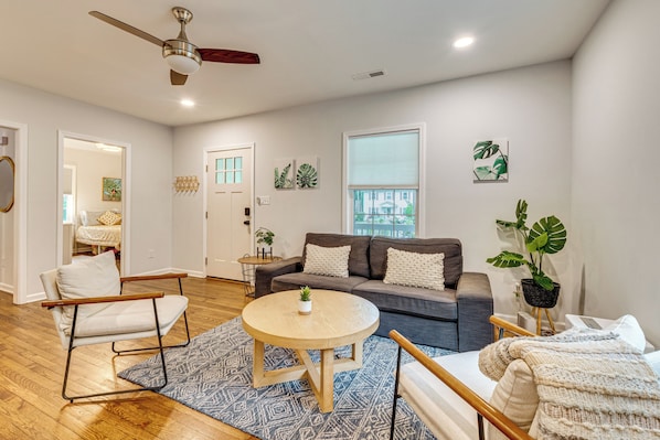A modern living room with a sofa, a coffee table, a chair, and a ceiling fan.