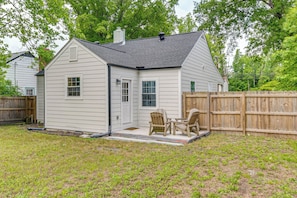 A single-story house with a covered patio, a wooden fence, and a grassy yard.