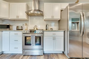 A modern kitchen with stainless steel appliances, white cabinetry, and a built-in oven.