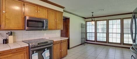Una cocina con armarios de madera, electrodomésticos de acero inoxidable y ventanas amplias.