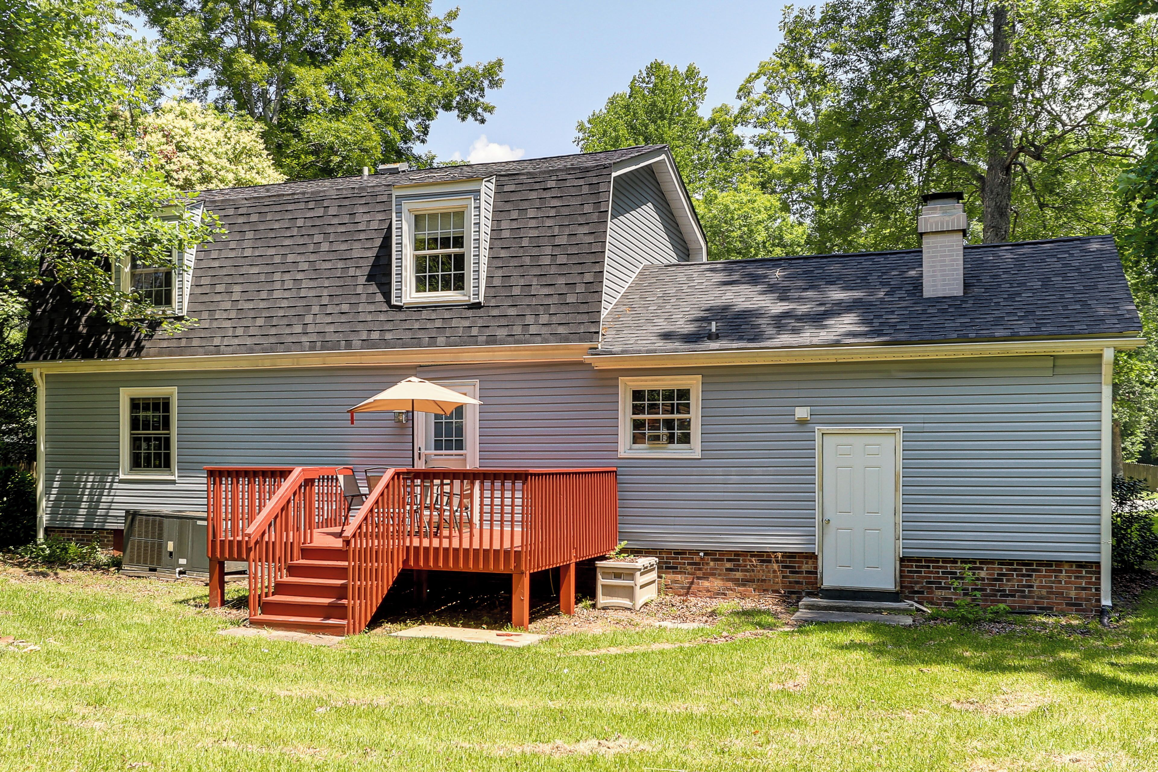 A two-story house with a deck, a chimney, and a door.
