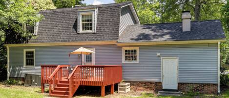 A two-story house with a deck, a chimney, and a door.